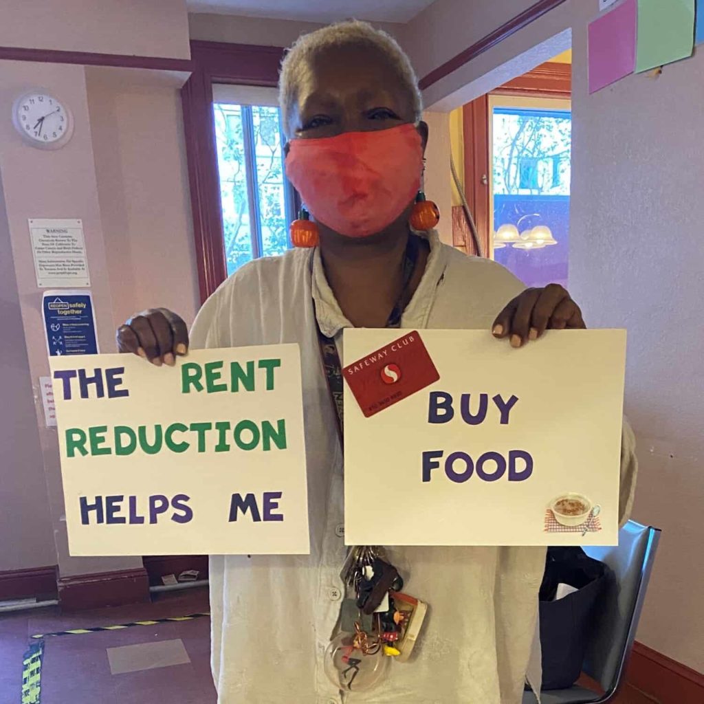 Woman holding signs reading: The rent reduction helps me buy food